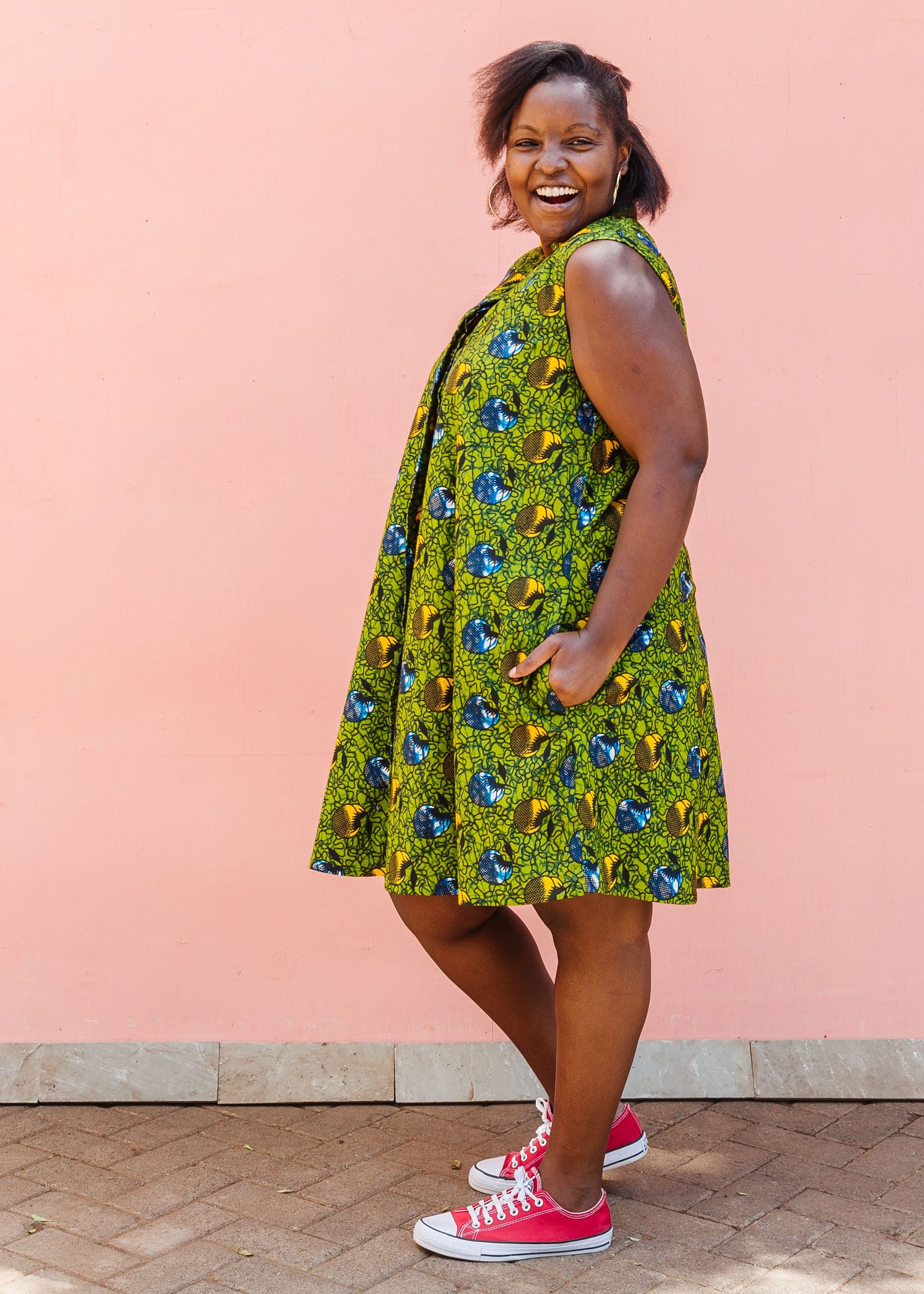 Model wearing green sleeveless dress with blue and yellow bubble design.