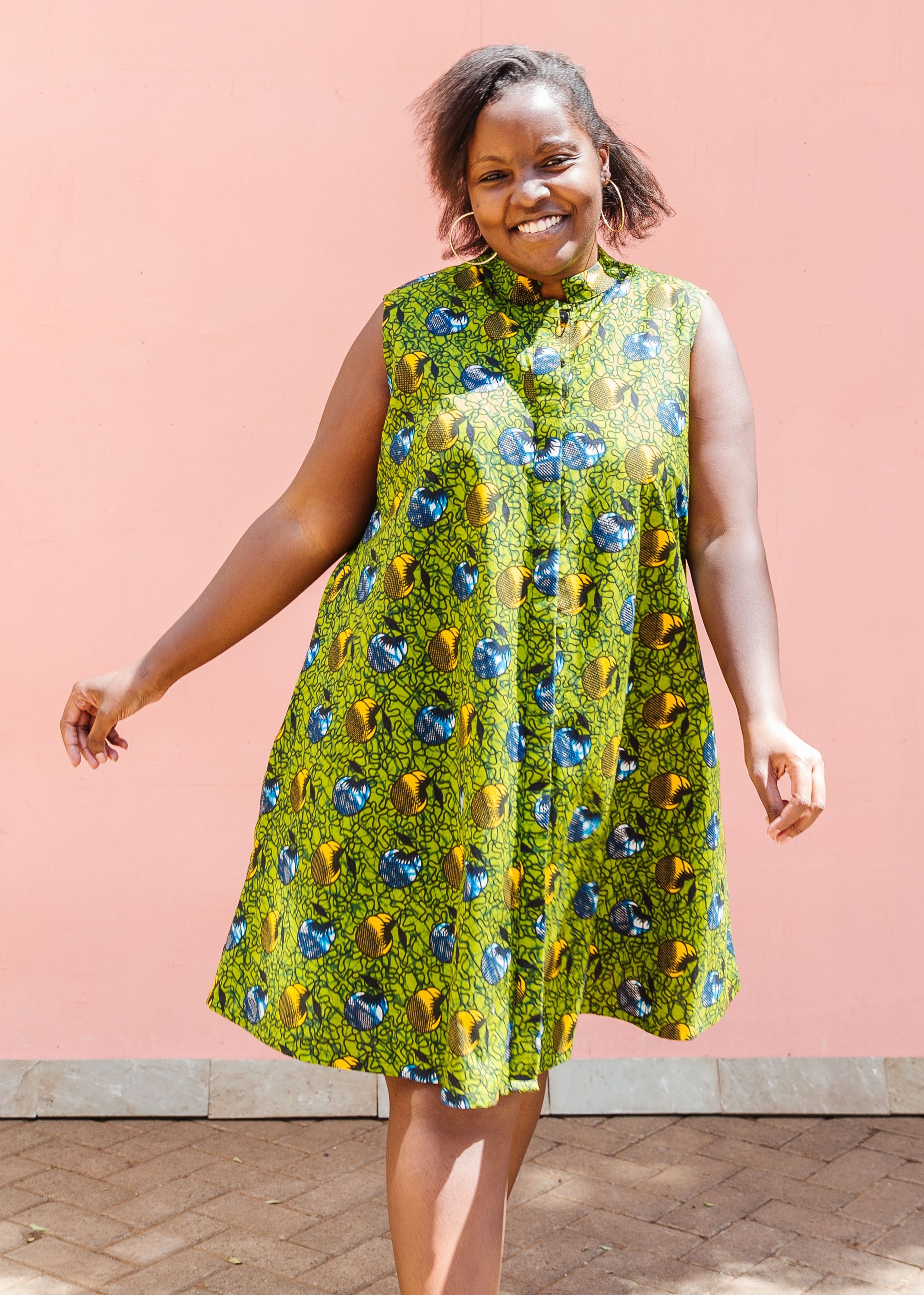 Model wearing green sleeveless dress with blue and yellow bubble design.