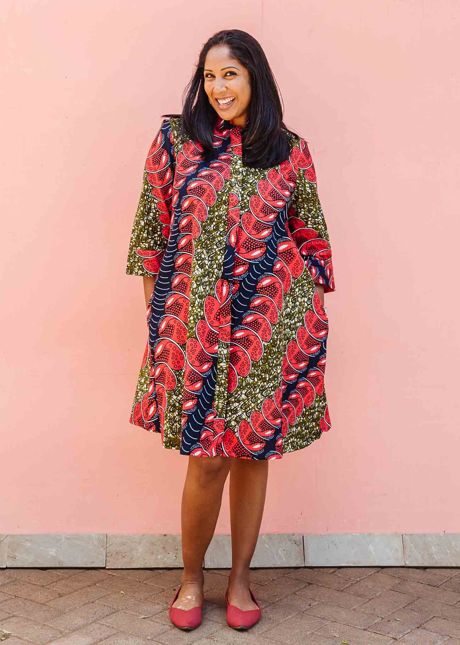 Model wearing green dress, with bold red and navy fish print.