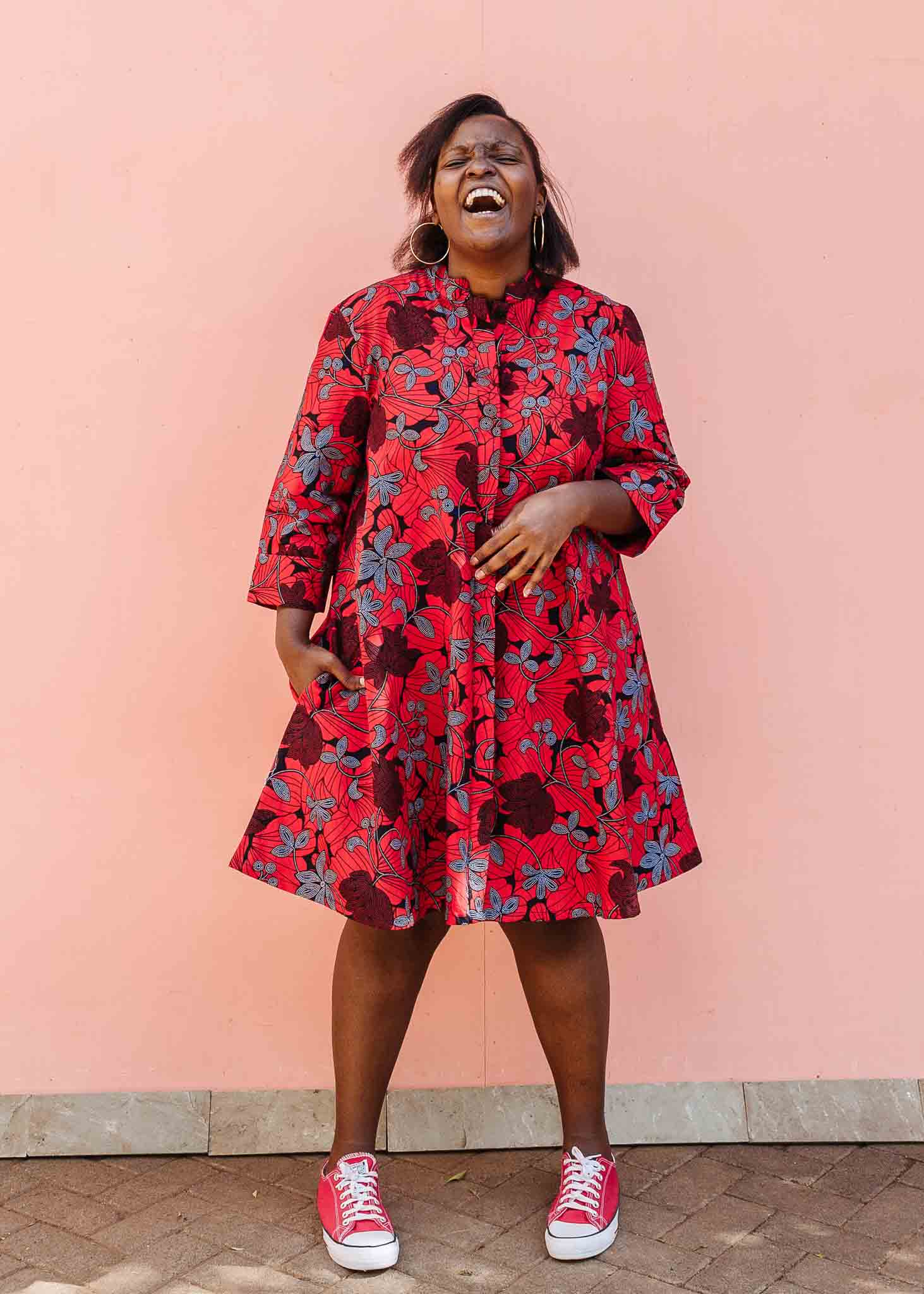 Model wearing red dress with floral vine print.