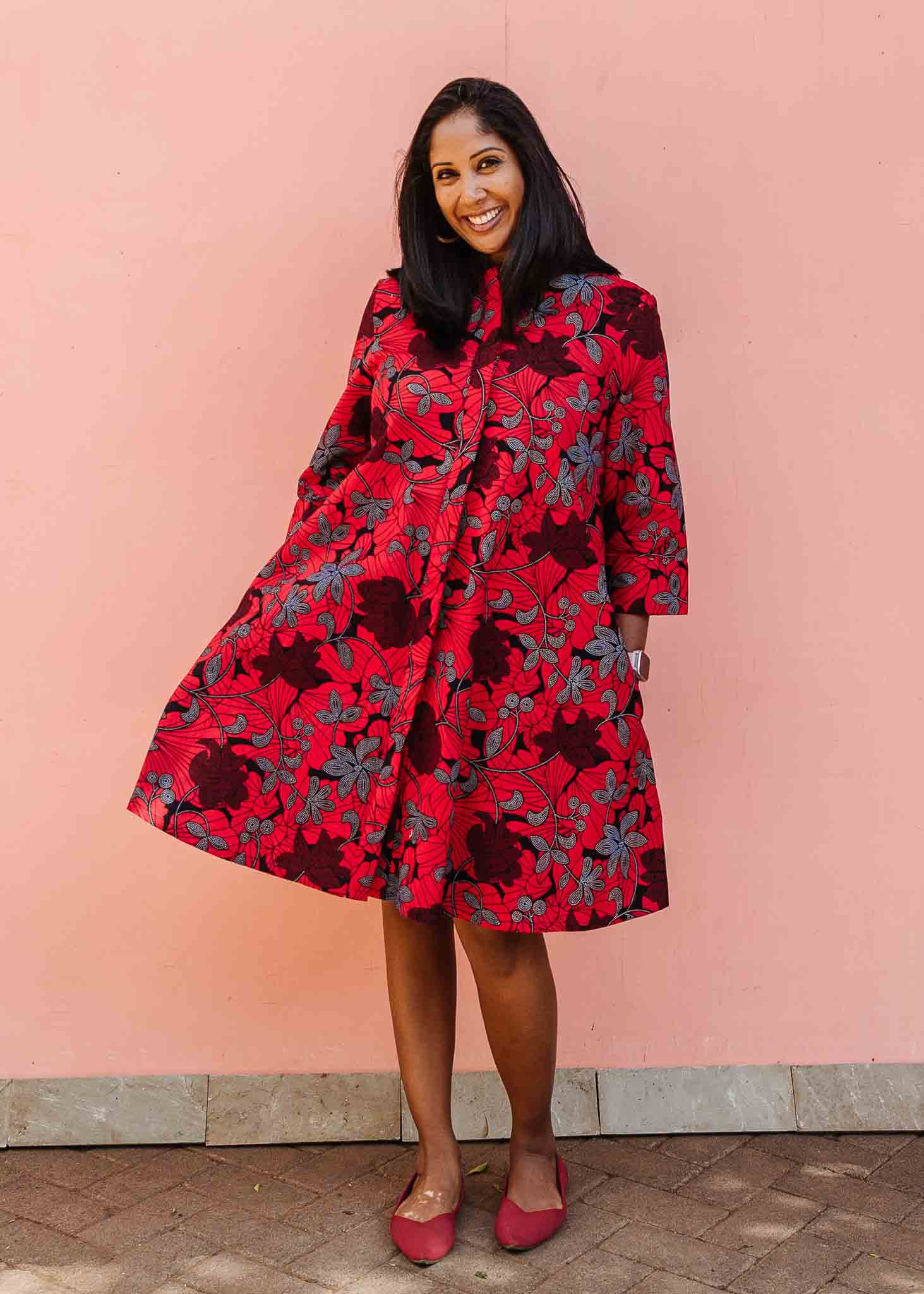 Model wearing red dress with floral vine print.
