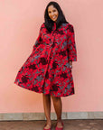 Model wearing red dress with floral vine print.