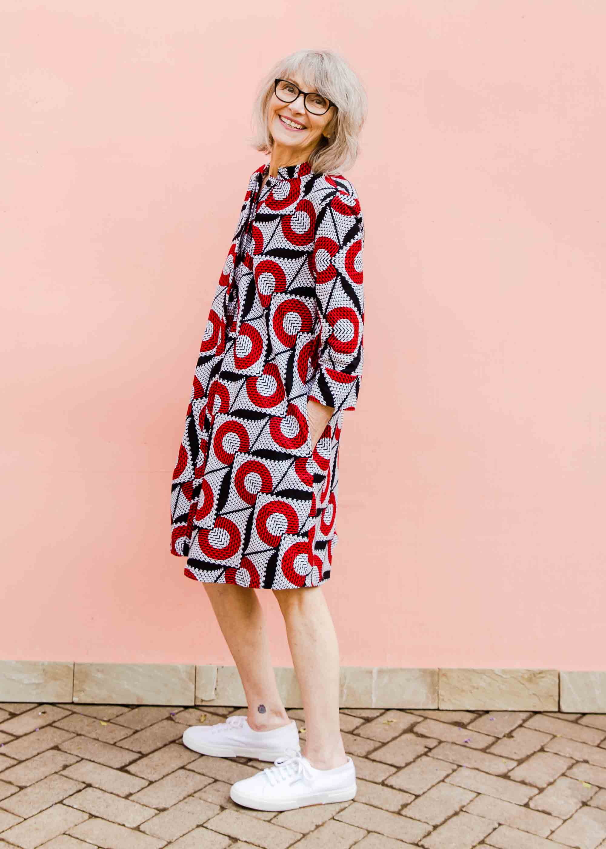 Model wearing white dress with red circles and black lines.