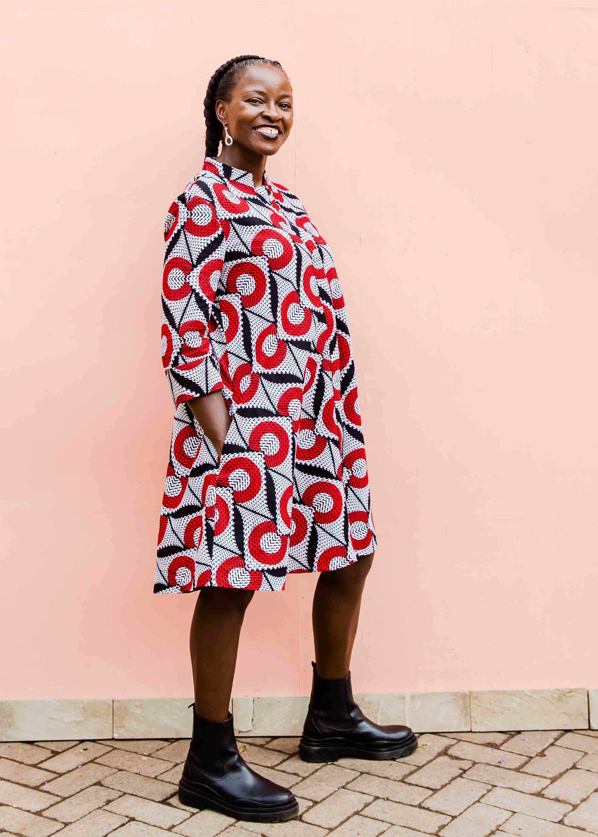 Model wearing white dress with red circles and black lines.