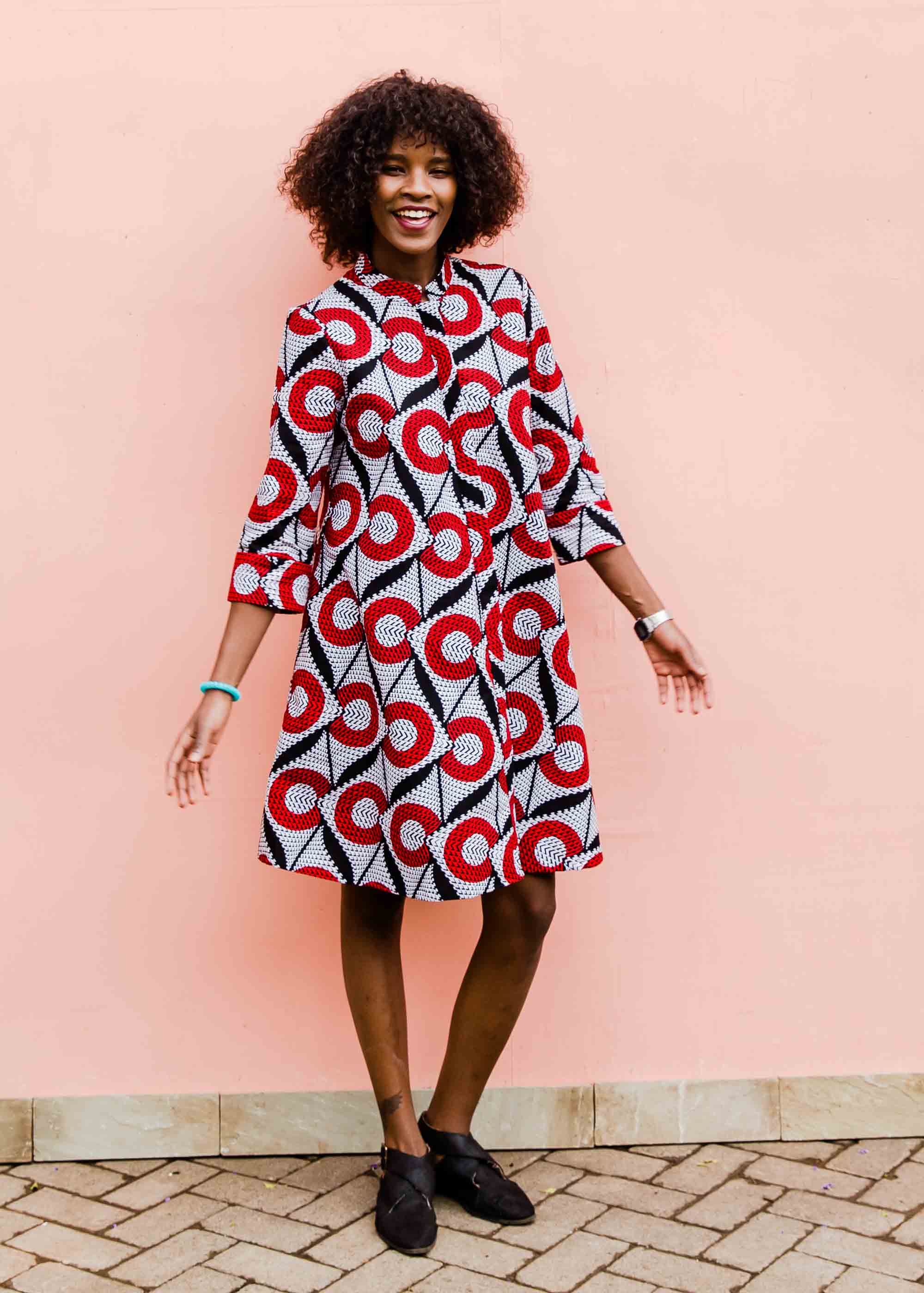 Model wearing white dress with red circles and black lines.