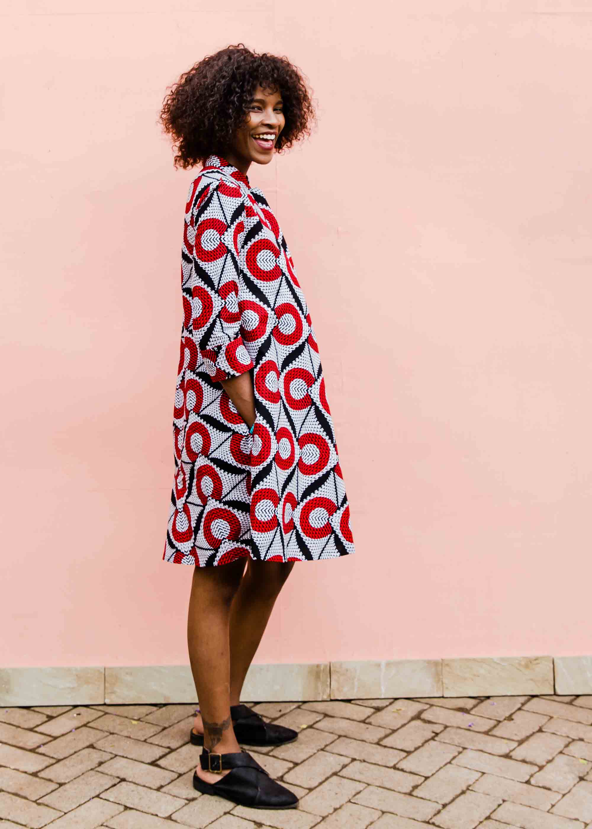 Model wearing white dress with red circles and black lines.