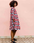 Model wearing white dress with red circles and black lines.