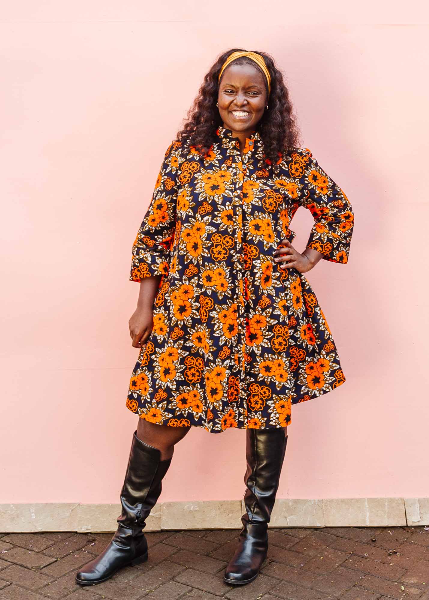 The model is wearing navy dress with orange, brown, black and white floral print