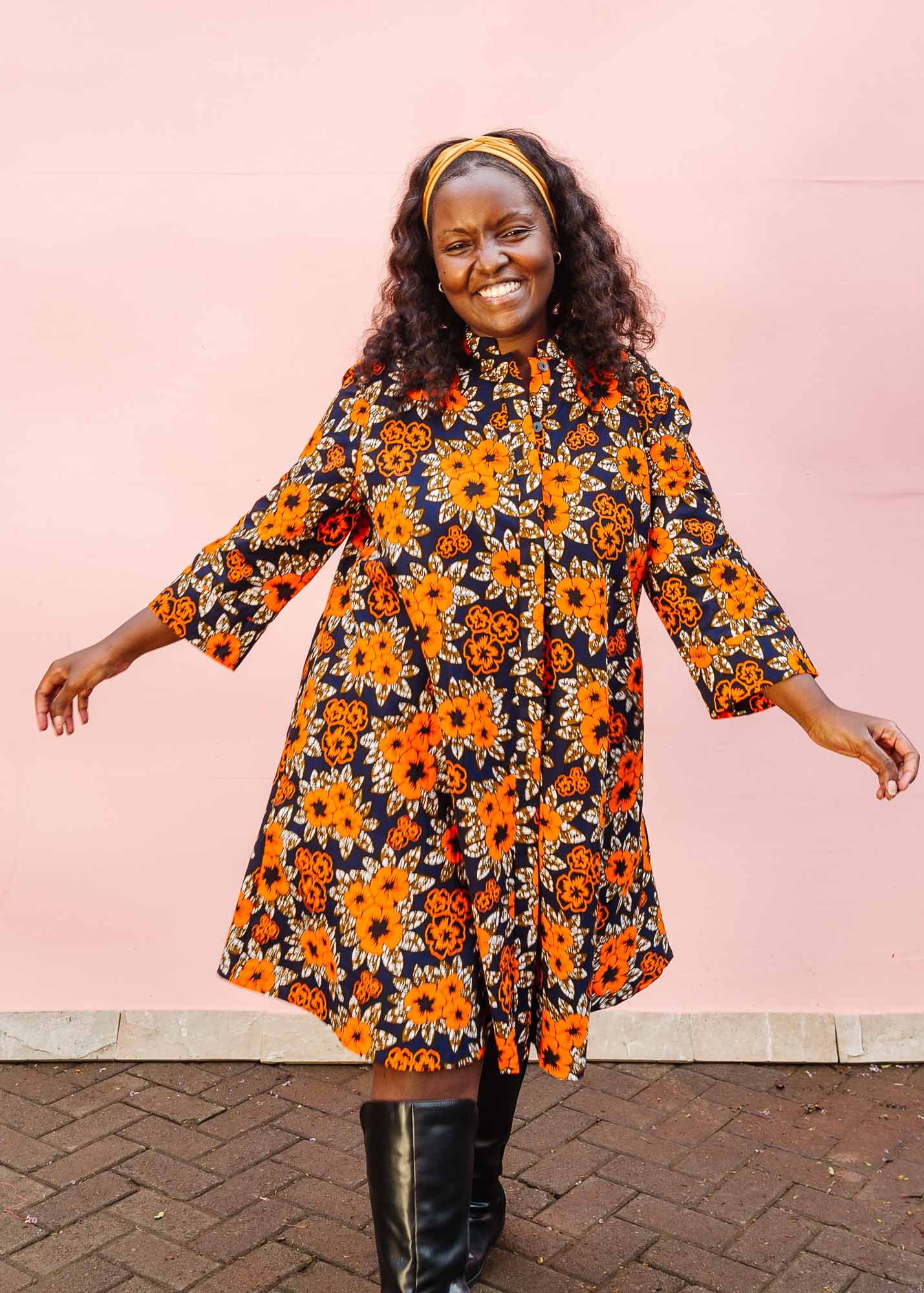 The model is wearing navy dress with orange, brown, black and white floral print