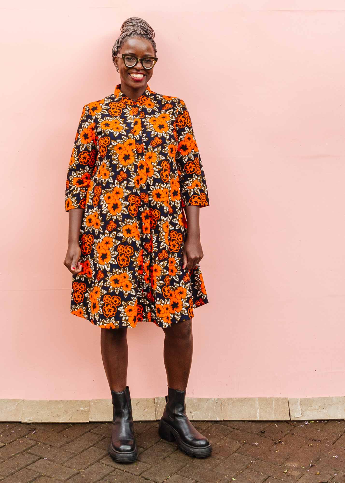 The model is wearing navy dress with orange, brown, black and white floral print