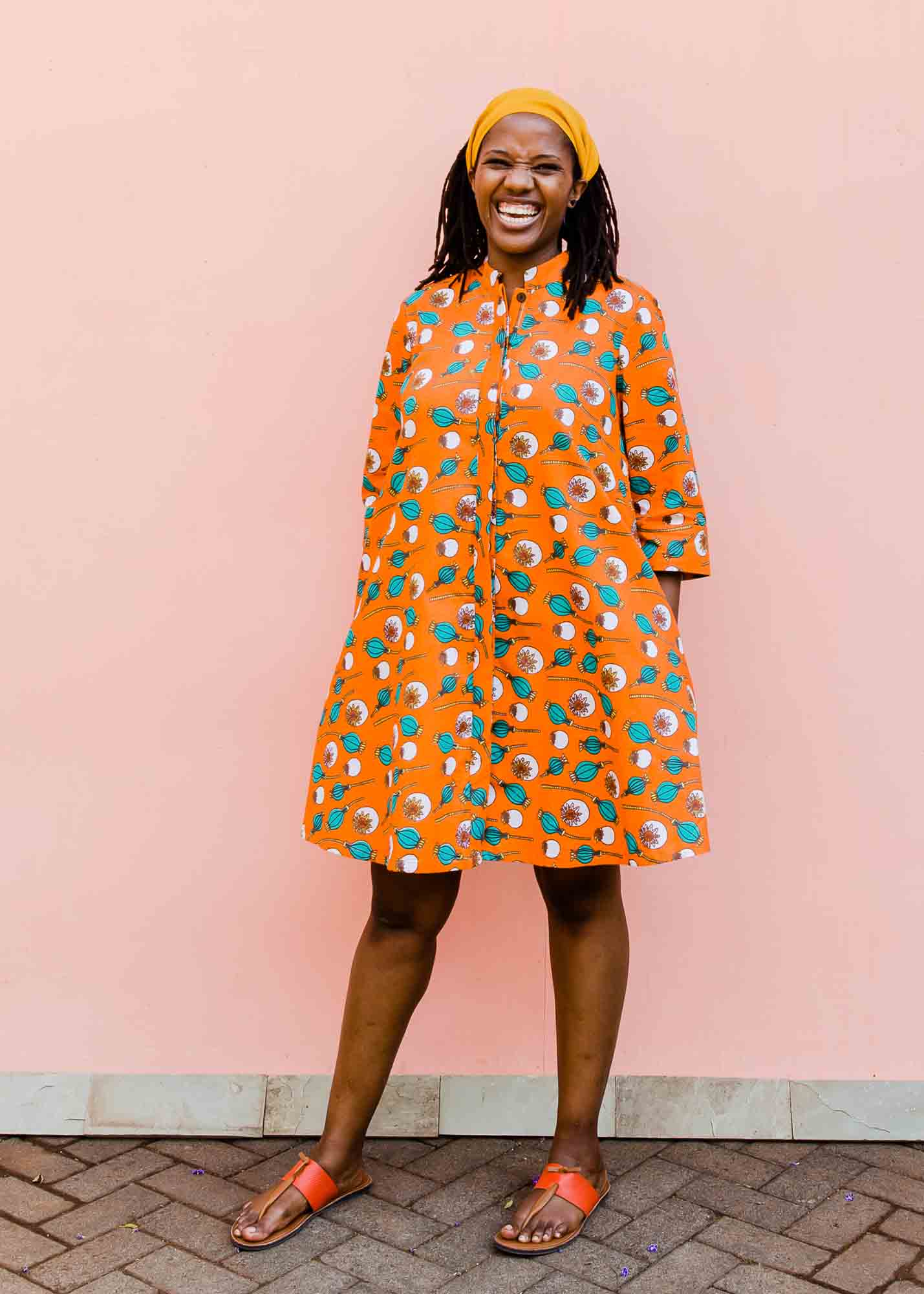 model wearing an orange, white and green plant design dress