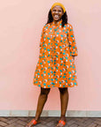 model wearing an orange, white and green plant design dress