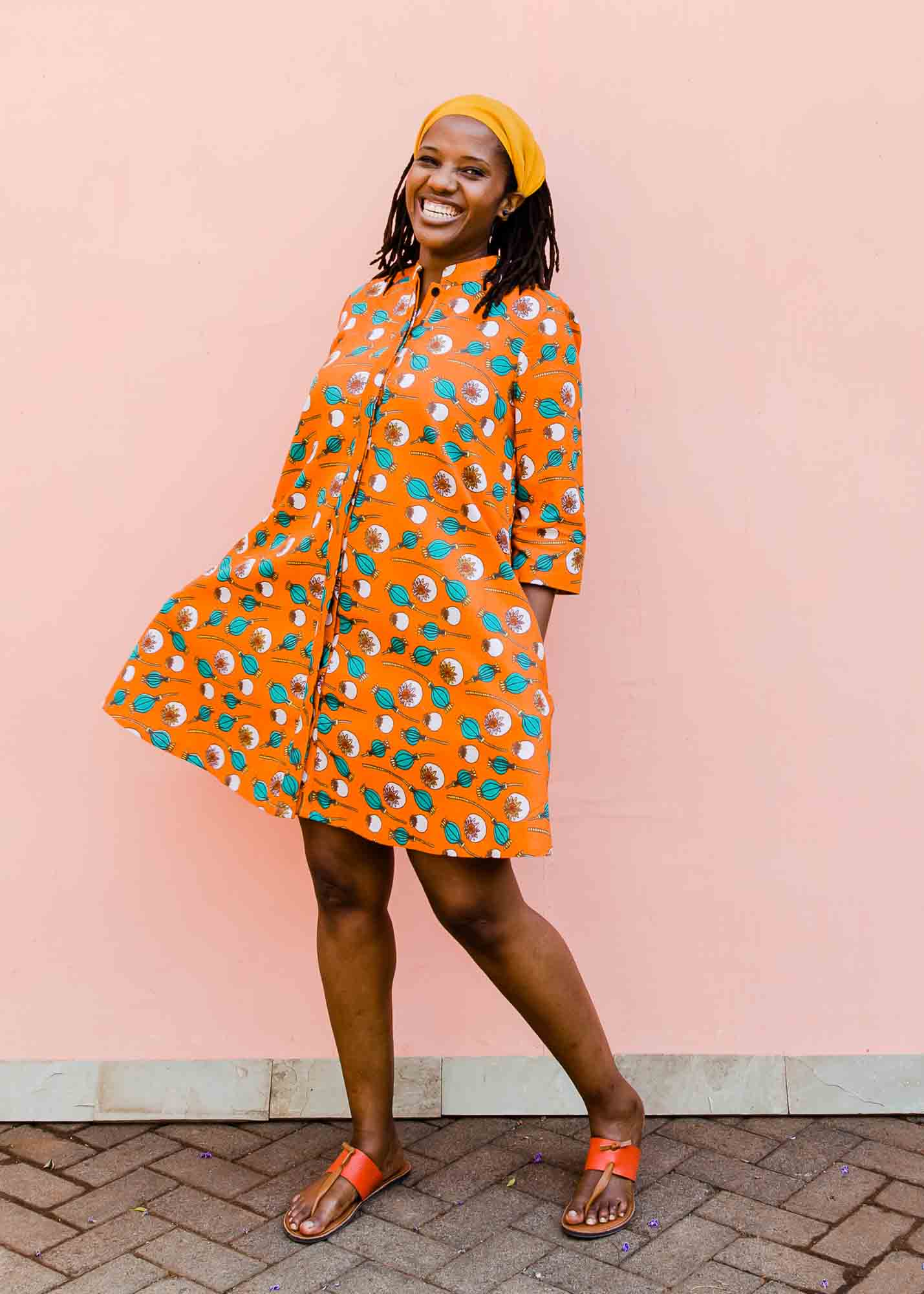 model wearing an orange, white and green plant design dress