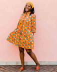 model wearing an orange, white and green plant design dress