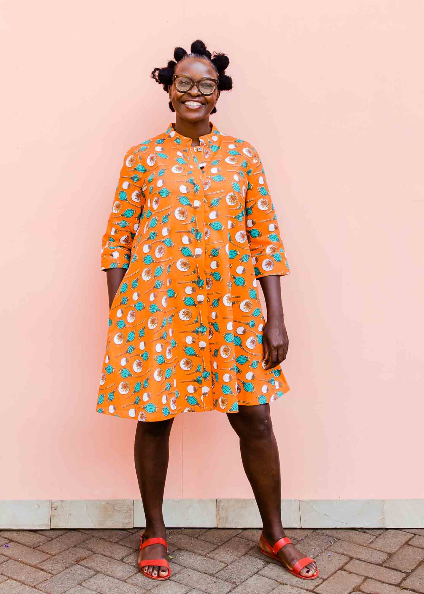 model wearing an orange, white and green plant design dress