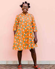 model wearing an orange, white and green plant design dress