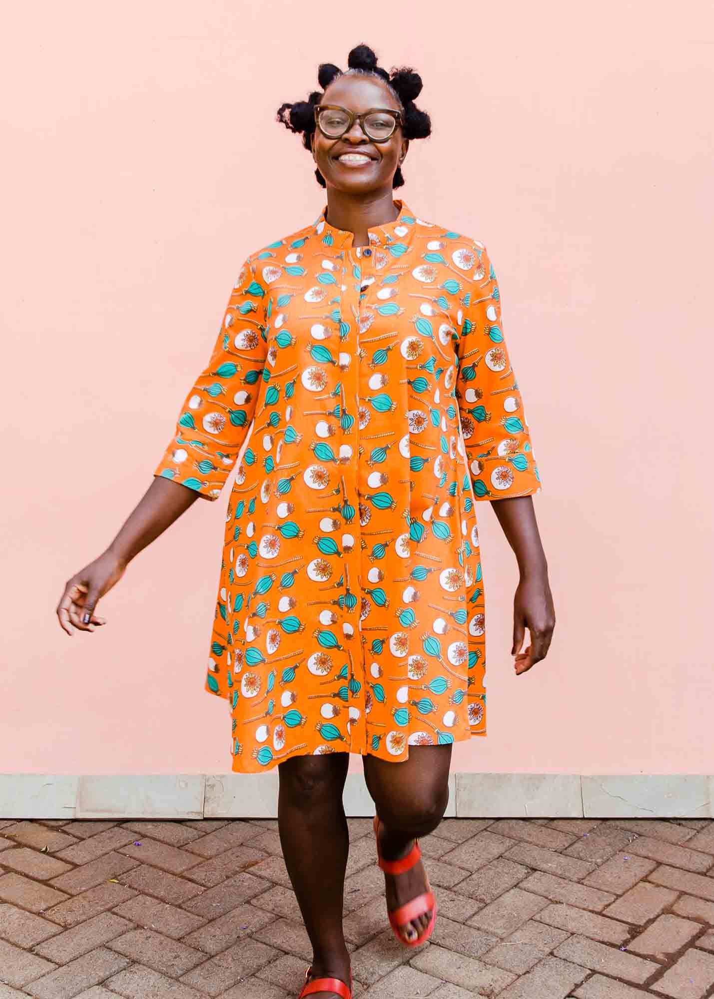 model wearing an orange, white and green plant design dress