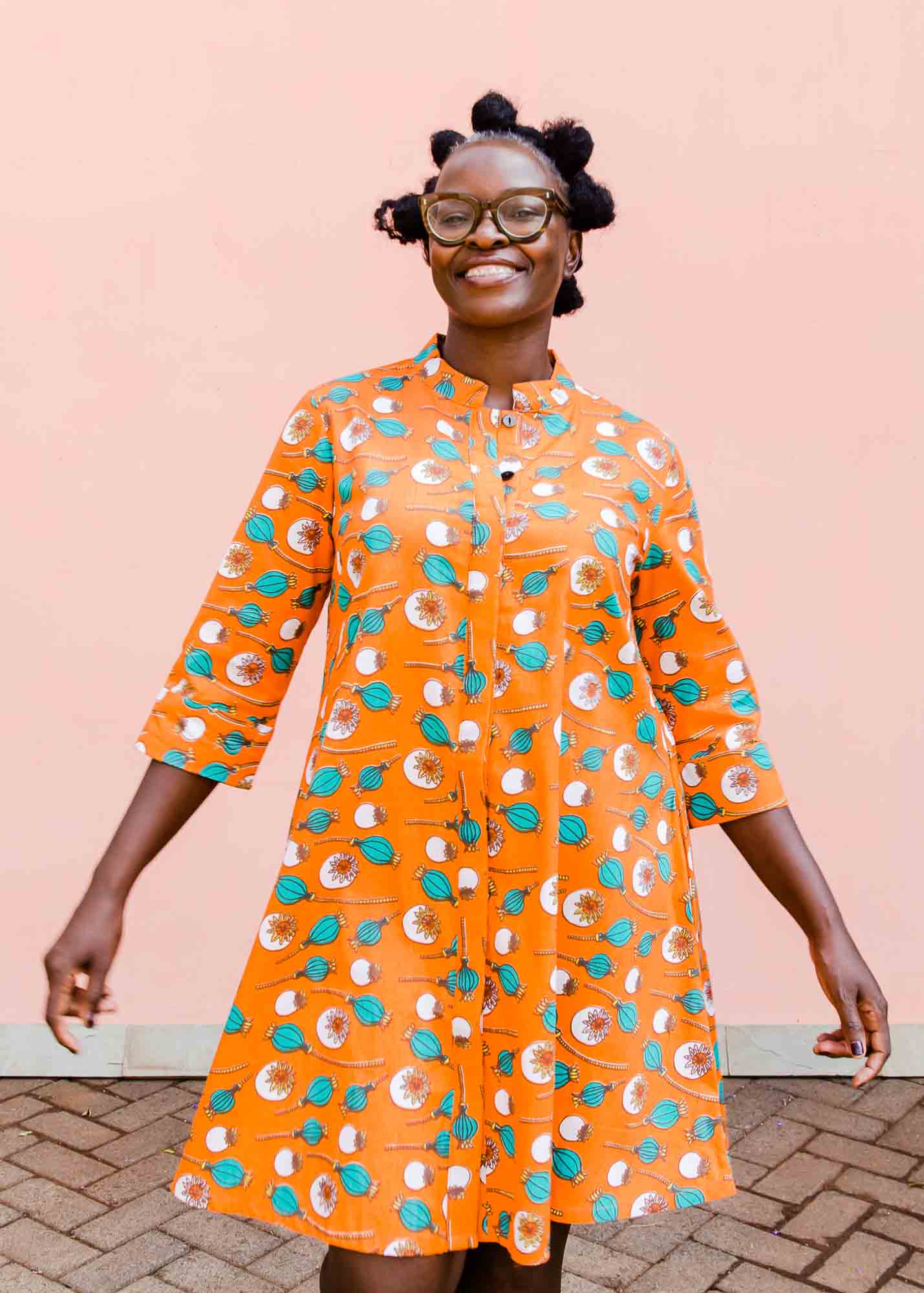 model wearing an orange, white and green plant design dress