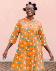 model wearing an orange, white and green plant design dress