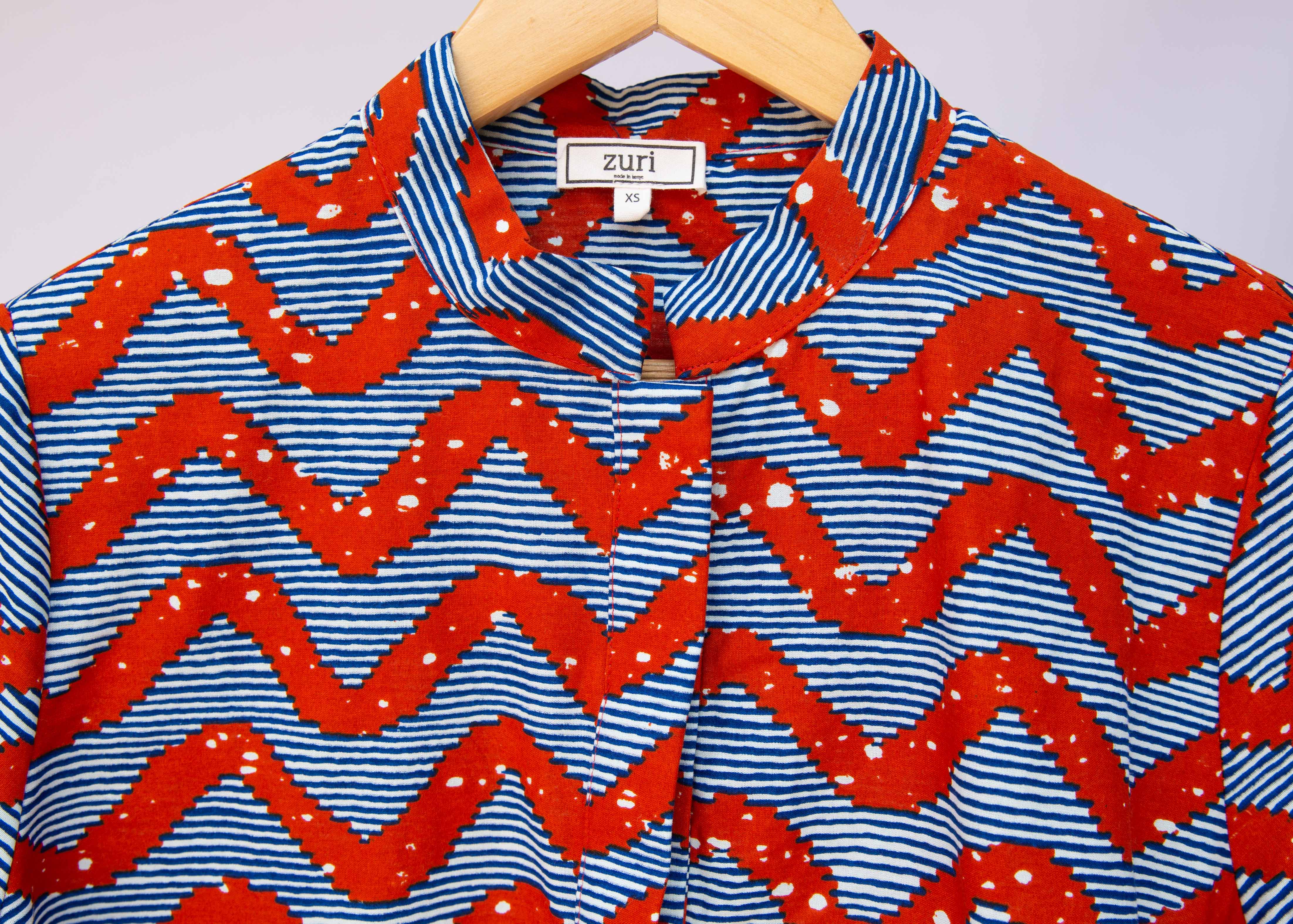 Close up display of blue and red zigzag print blouse.