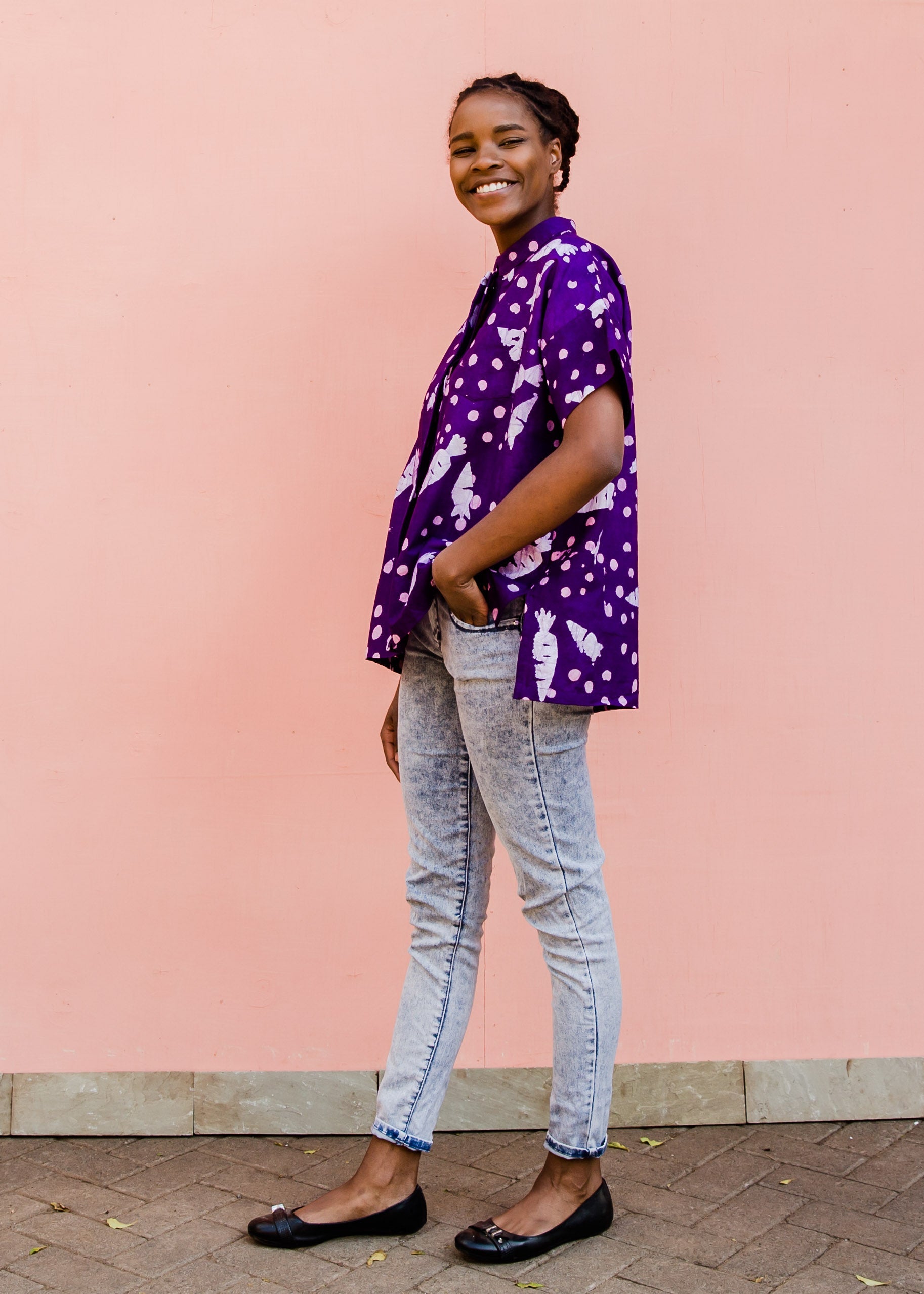 Model wearing purple shirt with white carrot print, paired with jeans and black flats.