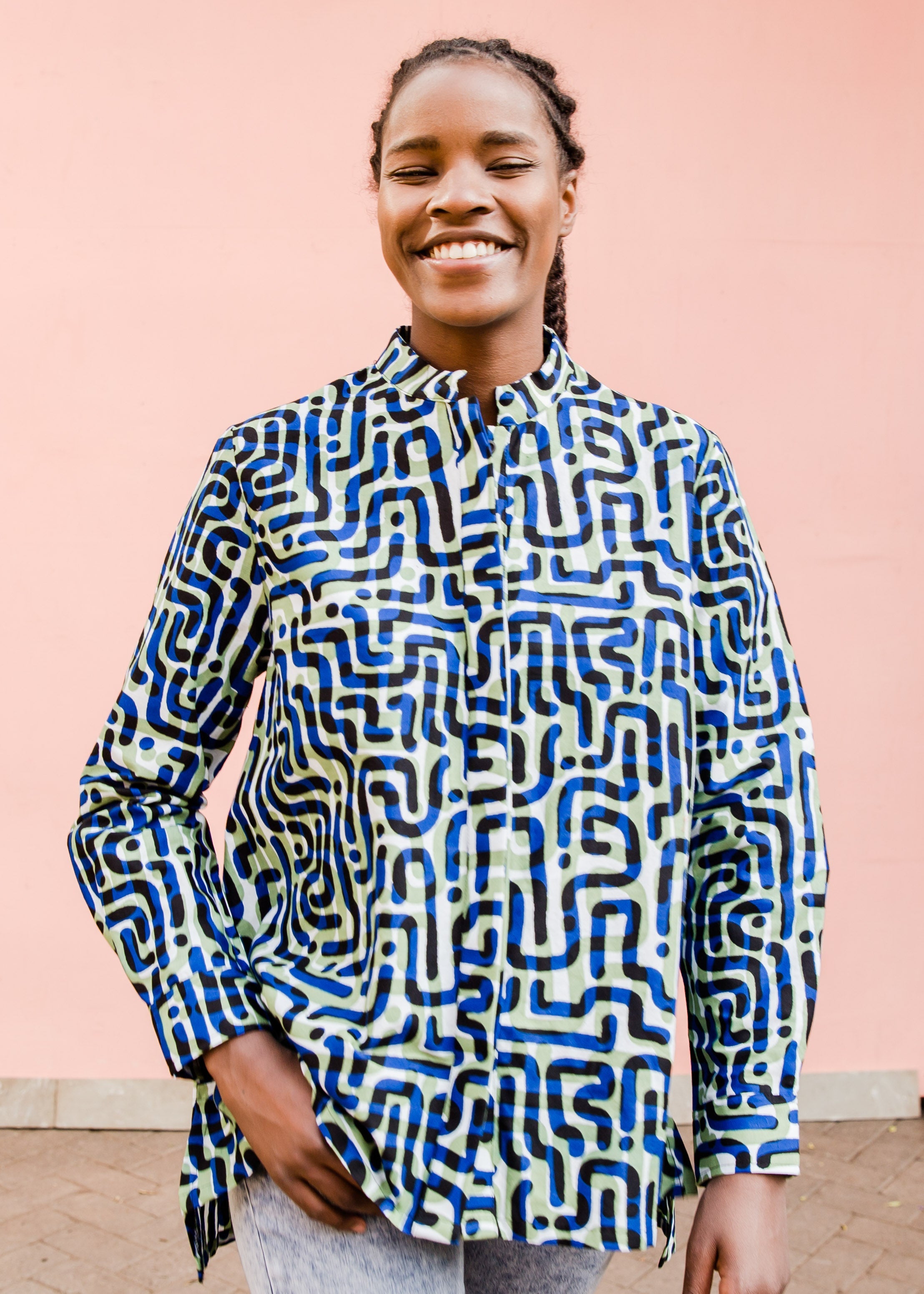Model wearing green, blue, black squiggle print, long sleeved blouse.