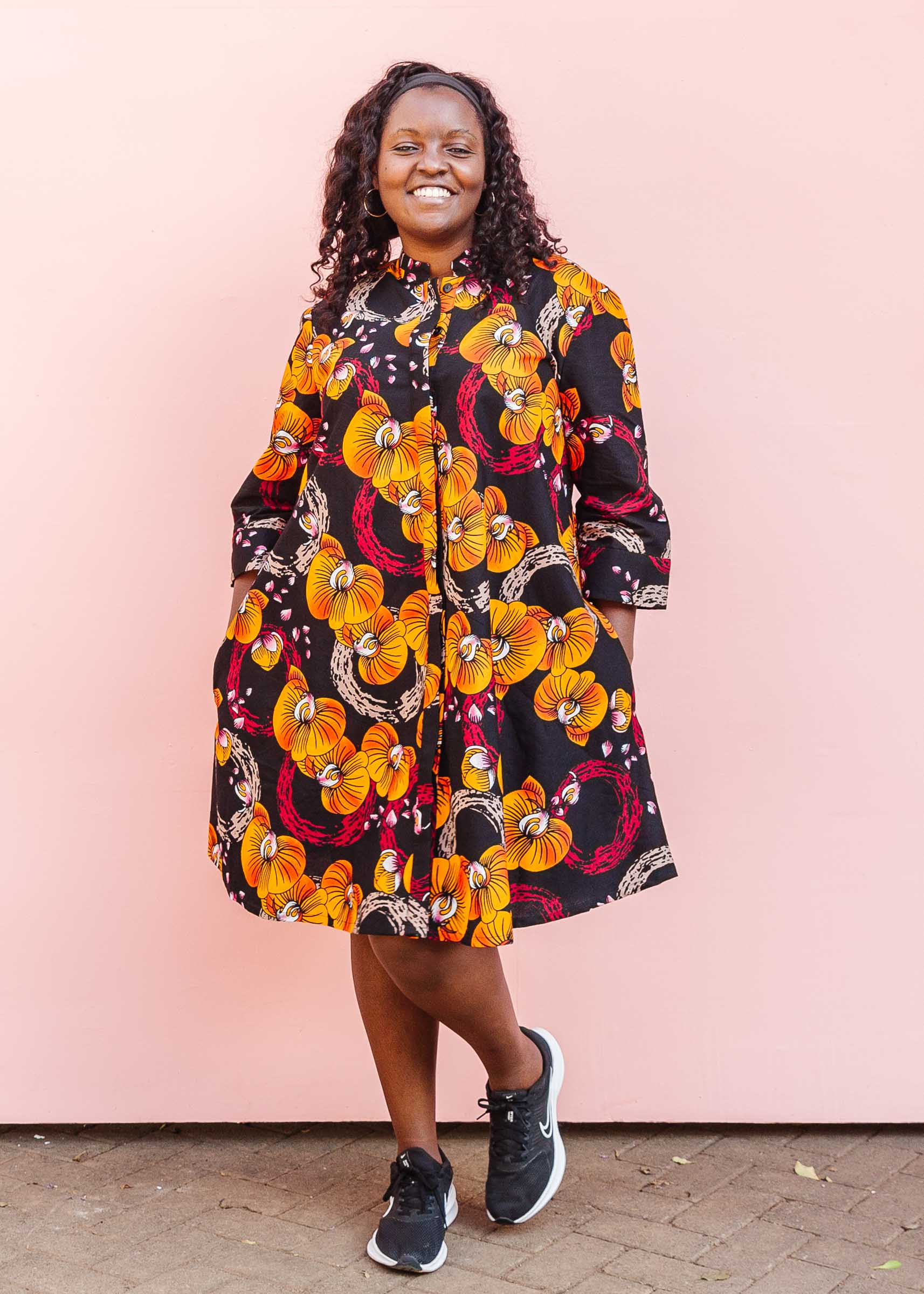 The model is wearing black dress with yellow and pink floral print.